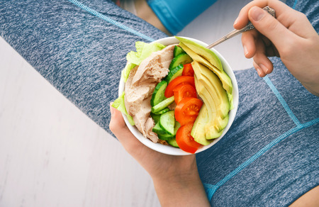 Woman eating a healthy salad after a workout.