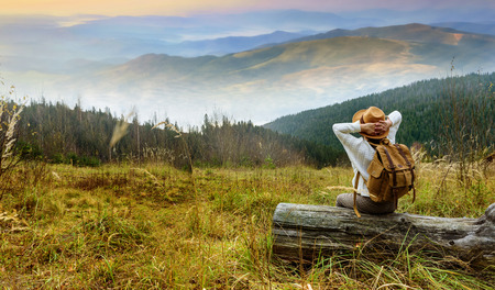 Woman traveler with backpack enjoying sunset on peak of mountain. Concept of travel.の写真素材
