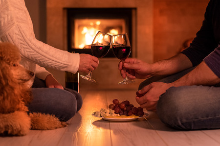 Young couple have a romantic dinner with wine over fireplaceの写真素材