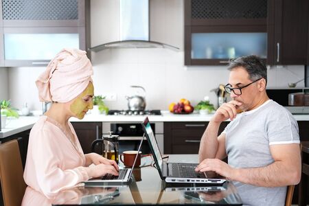 Woman applying facial clay mask. The adult woman and man are working remotely.の写真素材