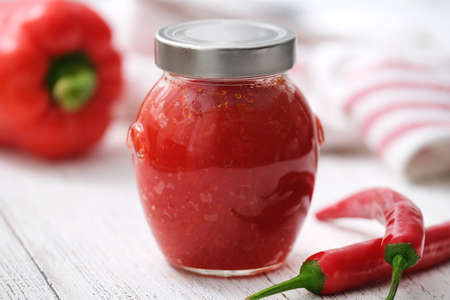 Sweet bell pepper and chili pepper sauce. Hot pepper jelly in a glass jar.の写真素材