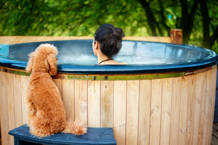 Young woman in an open-air bath with a view of the mountains. Young woman with her dog.の写真素材