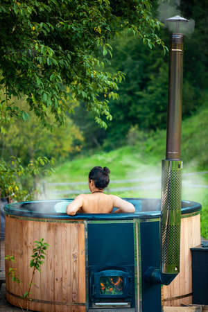 Young woman in an open-air bath with a view of the mountains.の写真素材