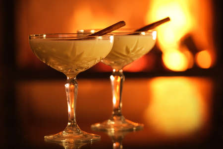 Two glasses with eggnog and cinnamon on the fireplace background. Close-up.の写真素材