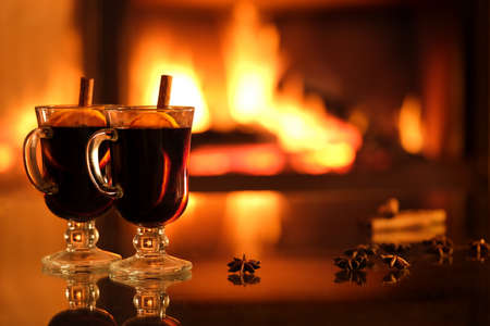 Two glasses with mulled wine on the fireplace background. Romantic concept. Background with text space.の写真素材