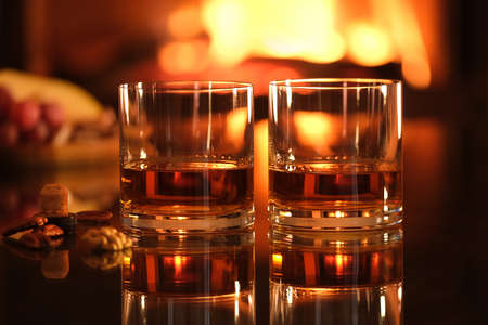 Two glasses with whiskey and serving on the fireplace background. Romantic dinner.の写真素材
