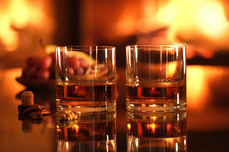 Two glasses with whiskey and serving on the fireplace background. Romantic dinner.の写真素材