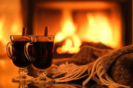 Two glasses with mulled wine and plaid on the fireplace background. Romantic concept. Background with text space.の写真素材