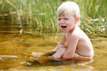 little girl sitting in riverの写真素材