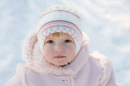 little girl outdoors in winter clothing closeup looking upの写真素材
