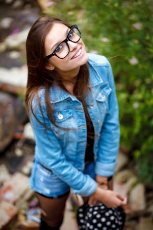 happy young female outdoors in jeans wear smiling wearing glasses and hat view from aboveの写真素材