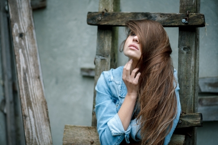 young female wearing jean jacket outdoors with  eye covered by long hairの写真素材