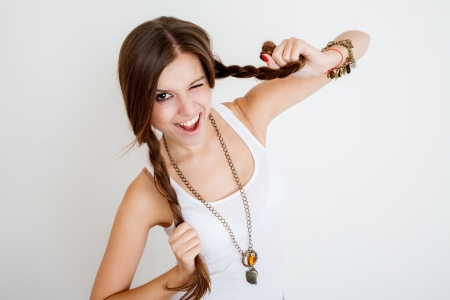 young female playing with her braids and winking on white background