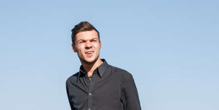 young male in black shirt looking away clear sky on background