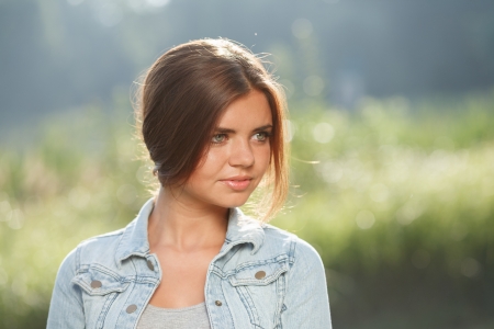 close-up portrait of beautiful teenage girl outdoors in jeans wear looking awayの写真素材