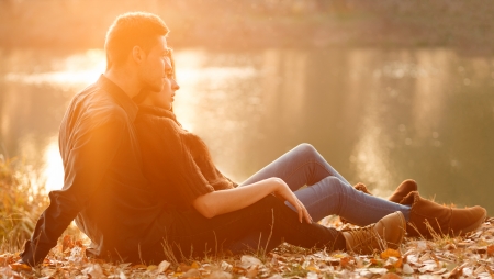 young couple sitting near lake  having good time sunsetの写真素材