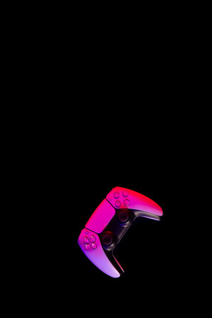 Modern white gamepad illuminated red and blue on a black background, top view.の写真素材