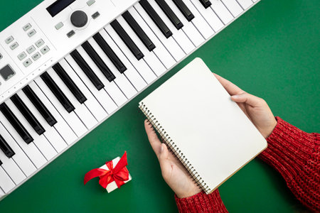 Musical Christmas background with keys and blank notepad in female hands, flat lay.の写真素材