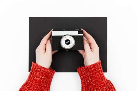 Old film camera in female hands on a black and white background, flat lay.の写真素材