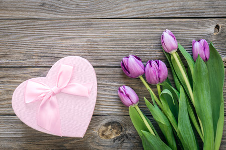 A bouquet of purple tulips and a gift box on a wooden background, top view.の写真素材