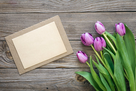 Bouquet of purple tulips and blank greeting card on wooden background.の写真素材