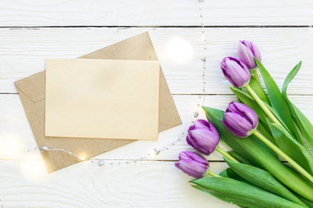 Tulip bouquet and envelope on white wooden background, copy space.の写真素材