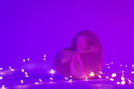 Gift box in the shape of a heart in neon lighting, copy space.の写真素材