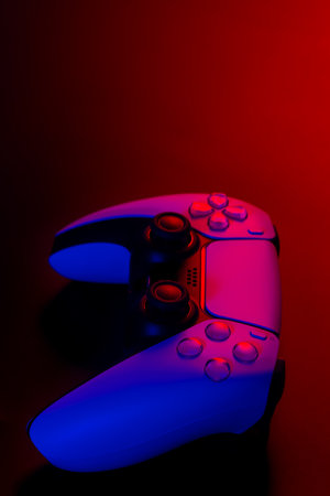 Modern white gamepad illuminated red and blue on a dark background.の写真素材