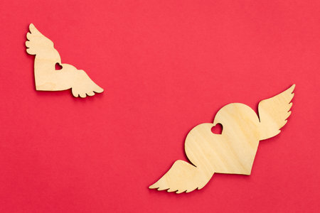 Decorative wooden hearts on a pink background, flat lay.