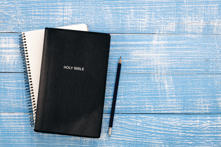 Holy bible book and notebook on blue wooden background, top view.