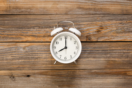 White alarm clock on a wooden background, top view.