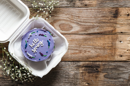Bento cake with the inscription Hello spring on a wooden background.の写真素材