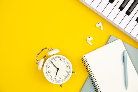 Alarm clock, notebooks and piano on yellow background, flat lay, copy space.の写真素材