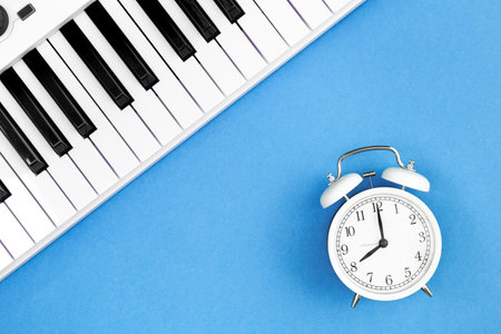 White alarm clock and piano on a blue background, flat lay.の写真素材