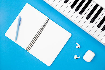 Blank notebook and piano on a blue background, flat lay, copy space.の写真素材