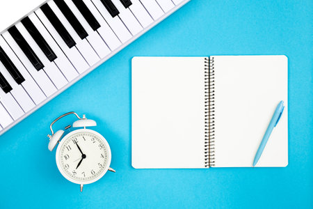 Blank notebook, piano and alarm clock on blue background, copy space.の写真素材