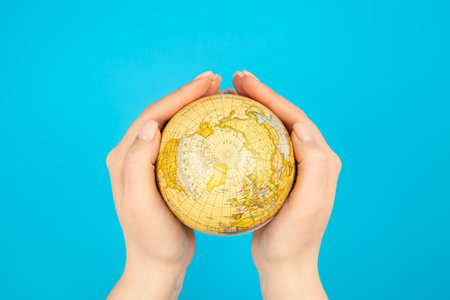 Earth globe in female hands on a blue background isolated, top view.の写真素材