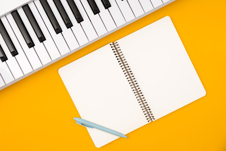 Piano and notebook on orange background, flat lay, copy space.の写真素材