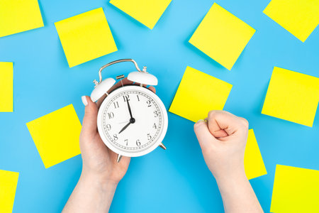 White alarm clock and yellow paper reminder, flat lay.の写真素材