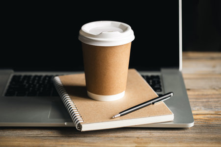 Eco-Friendly Work Concept, Disposable Cup and Recycled Notepad on Laptop.