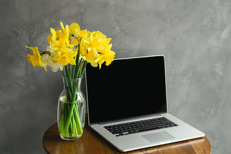 Spring Productivity. A Desktop with Yellow Daffodils and Laptop.の写真素材