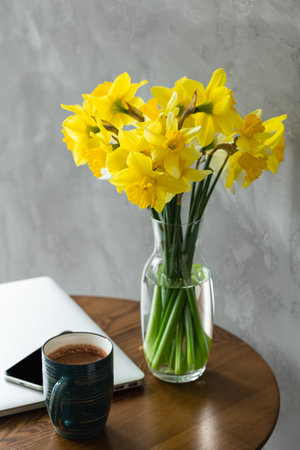 Spring Productivity. A Desktop with Yellow Daffodils, Laptop and Coffee.の写真素材