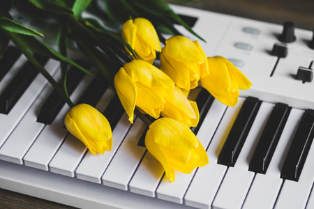 Yellow flowers tulips on the keys of a white piano, close-up.の写真素材