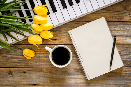 Piano, notebook, coffee and a bouquet of flowers on a wooden background.の写真素材
