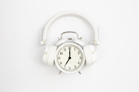 Alarm clock with headphones on white background, top view.の写真素材