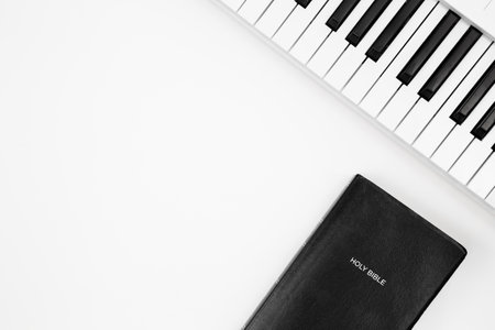 Music synthesizer keyboard and Bible on white background, top view.の写真素材