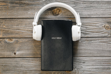 Top view of holy Bible with headphones on wooden surface.の写真素材