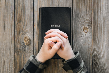 Black Holy Bible in male hands on a wooden background, top view.の写真素材