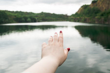 A woman stretches hand to nature, a womans hand on the background of the river.の写真素材