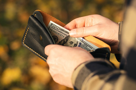 Open wallet with dollar bills in male hands, close-up.